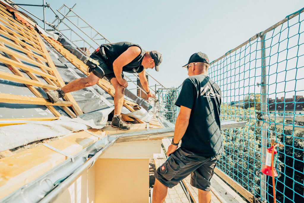 Zwei Monteure der Dachbau Stefan Höft GmbH decken ein Steildach ein